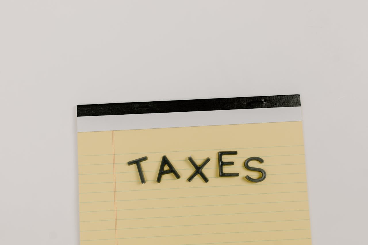 A flat lay of the word 'TAXES' on a yellow notepad, ideal for financial content.